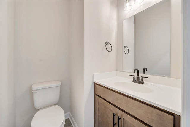 half bath featuring vanity, baseboards, and toilet