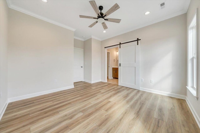 unfurnished bedroom featuring visible vents, a barn door, ornamental molding, light wood-type flooring, and multiple windows
