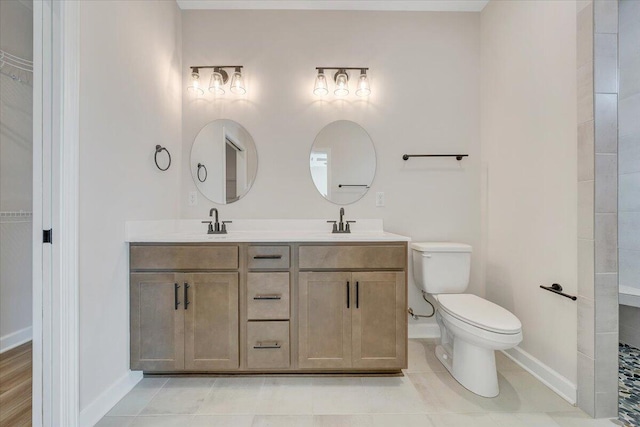 bathroom with a sink, toilet, double vanity, and baseboards