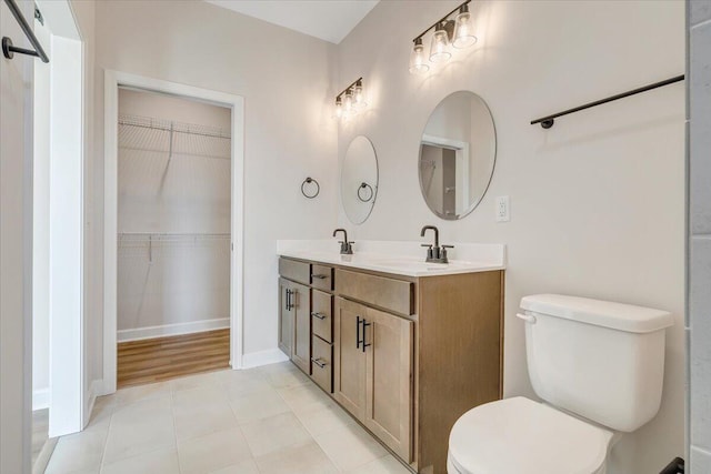 bathroom with a sink, toilet, double vanity, and tile patterned flooring