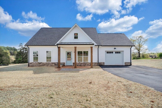 modern farmhouse featuring roof with shingles, driveway, board and batten siding, an attached garage, and a standing seam roof