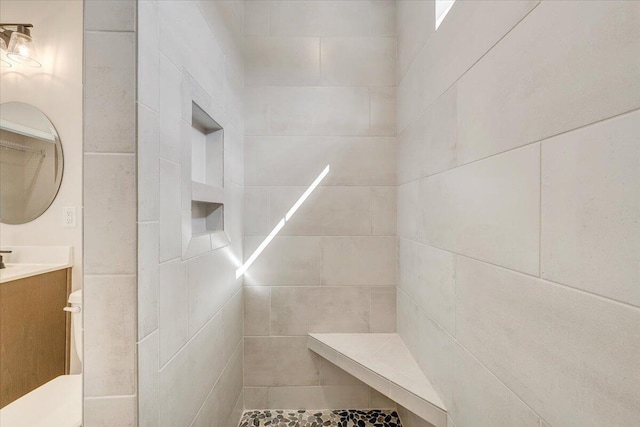 bathroom featuring toilet, a tile shower, and vanity