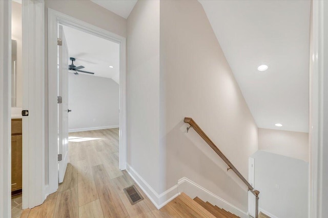 hallway featuring visible vents, baseboards, an upstairs landing, and light wood-style floors