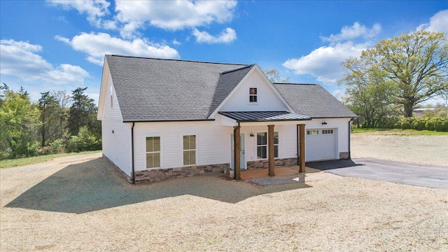 modern inspired farmhouse featuring a shingled roof, aphalt driveway, a garage, and stone siding