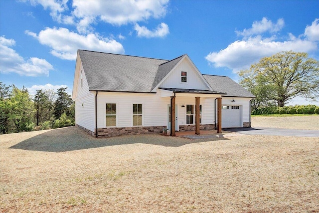 modern farmhouse with board and batten siding, aphalt driveway, a garage, stone siding, and a shingled roof