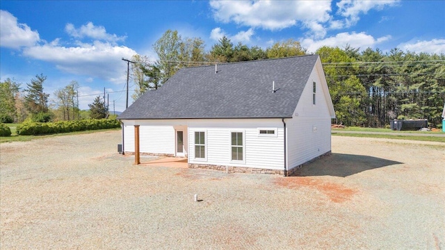 view of side of home with roof with shingles