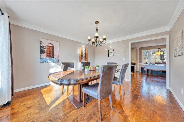 dining room with an inviting chandelier, crown molding, baseboards, and wood-type flooring