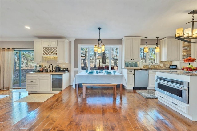 kitchen featuring backsplash, wine cooler, hanging light fixtures, stainless steel appliances, and wood-type flooring