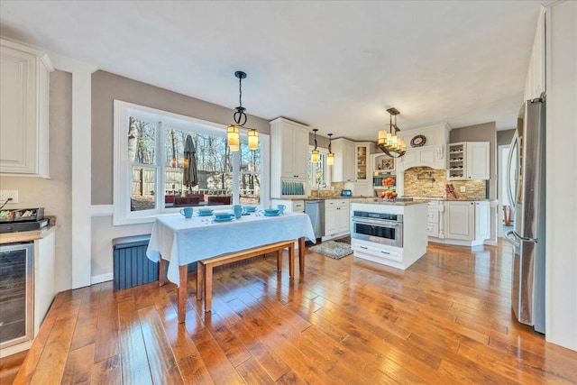 dining area featuring an inviting chandelier, light wood-style flooring, radiator, and beverage cooler