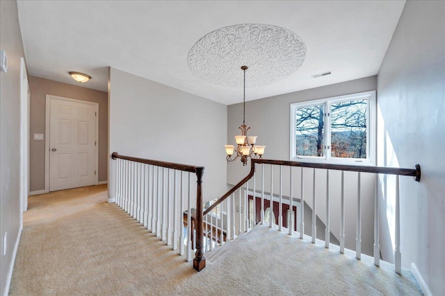 stairs with a chandelier, visible vents, carpet flooring, and baseboards