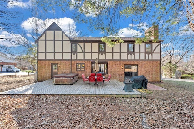 rear view of property featuring brick siding, a hot tub, a wooden deck, stucco siding, and a chimney