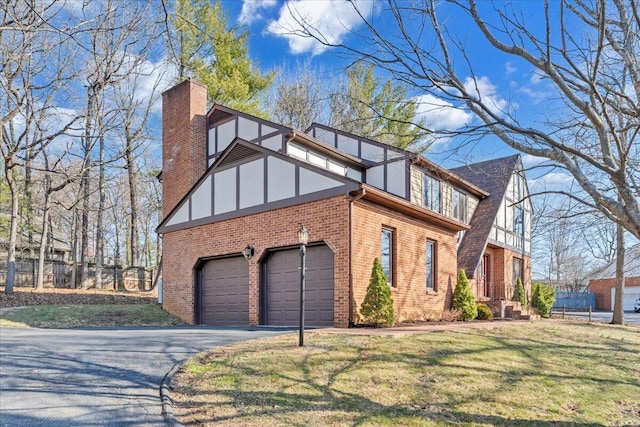 view of property exterior with brick siding, fence, aphalt driveway, a lawn, and a chimney