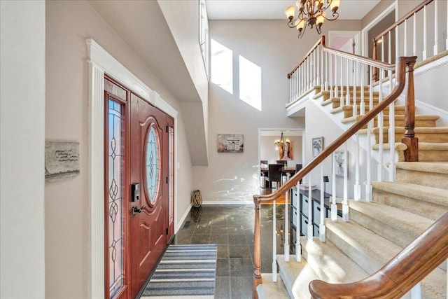 entryway with stairs, a high ceiling, a notable chandelier, and baseboards