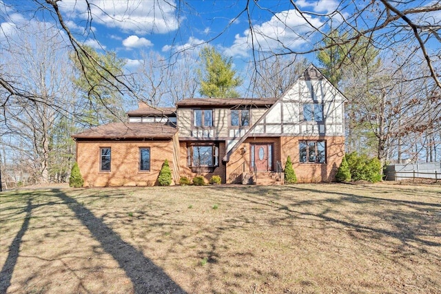 tudor house featuring brick siding, a chimney, and a front lawn