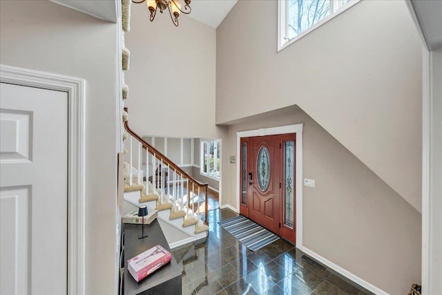 foyer featuring visible vents, granite finish floor, baseboards, a towering ceiling, and stairs