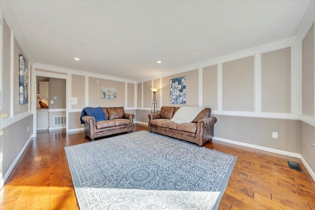 living room featuring visible vents, ornamental molding, baseboards, and hardwood / wood-style floors