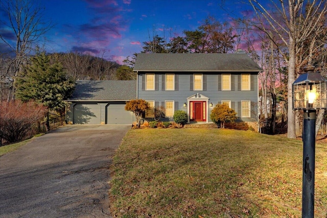 colonial-style house with a garage, driveway, and a front yard