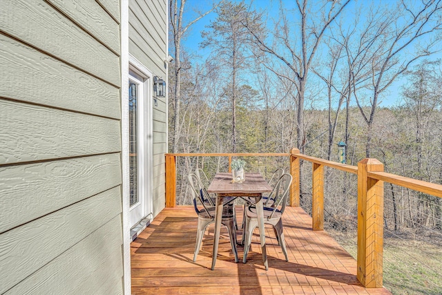 deck featuring a forest view and outdoor dining space