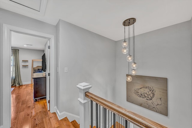 hall featuring baseboards, an upstairs landing, and wood finished floors