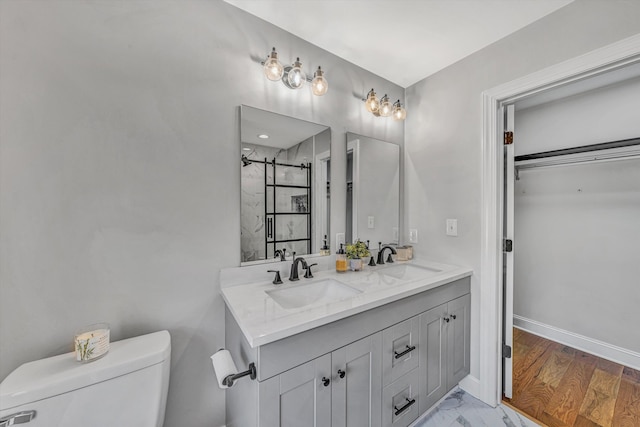 bathroom with walk in shower, a sink, toilet, and baseboards