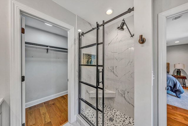 bathroom with a marble finish shower, baseboards, visible vents, connected bathroom, and wood finished floors