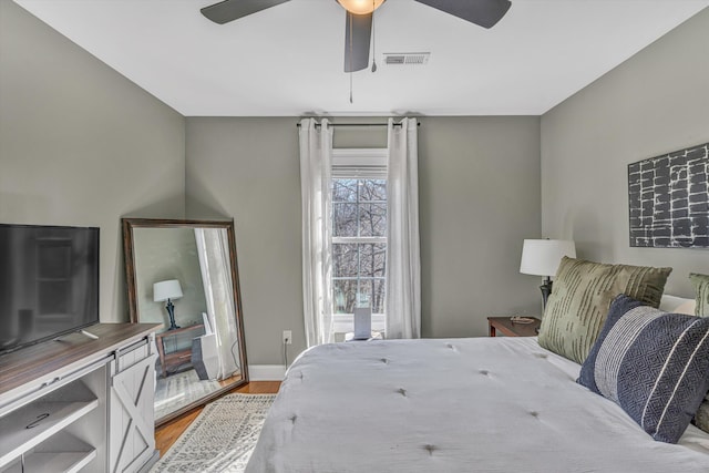 bedroom with baseboards, a ceiling fan, visible vents, and light wood-style floors