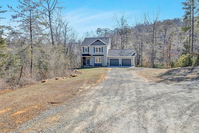 colonial inspired home with a garage, driveway, and a forest view