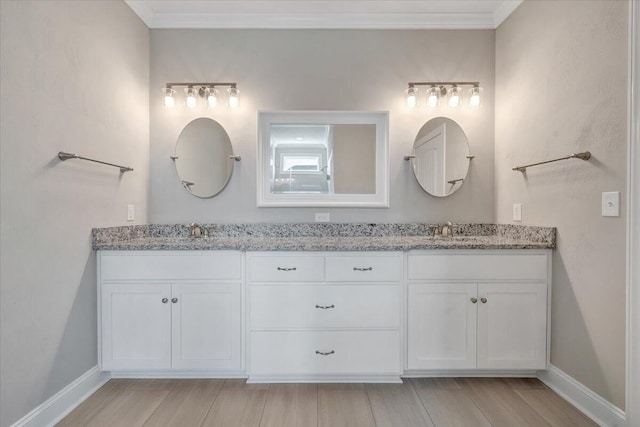bathroom with double vanity, wood finished floors, ornamental molding, and a sink