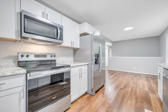 4438 Stonewall Rd NW, Roanoke, VA 24017 - kitchen with appliances with stainless steel finishes, white cabinetry, light wood-type flooring, and light stone counters