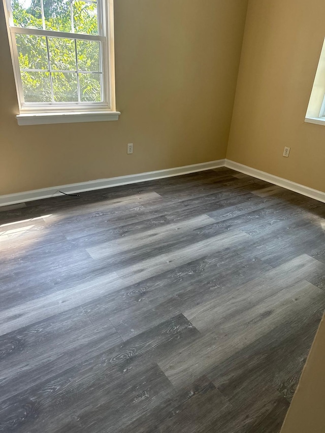 spare room featuring dark wood finished floors and baseboards