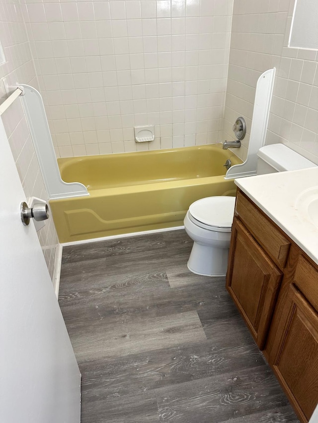 bathroom with toilet, washtub / shower combination, wood finished floors, and vanity