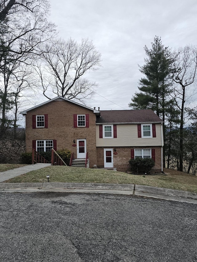 view of front facade featuring brick siding, a front lawn, and entry steps