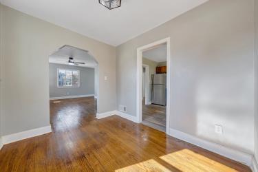 unfurnished room with baseboards, arched walkways, and wood finished floors