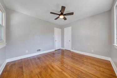 spare room with visible vents, ceiling fan, baseboards, and wood finished floors