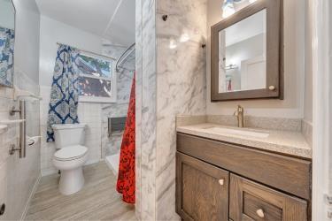 bathroom featuring toilet, wood finished floors, vanity, tile walls, and a shower