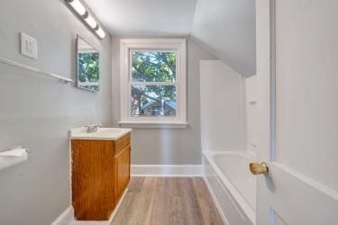 full bath featuring lofted ceiling, baseboards, wood finished floors, and vanity