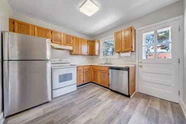 kitchen featuring stainless steel appliances, light countertops, light wood-style flooring, and under cabinet range hood