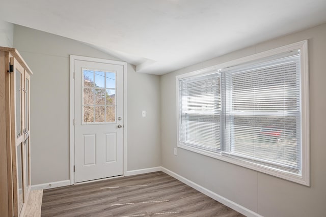 entryway with vaulted ceiling, wood finished floors, and baseboards