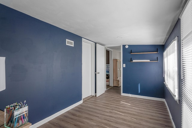 empty room featuring baseboards, visible vents, and wood finished floors