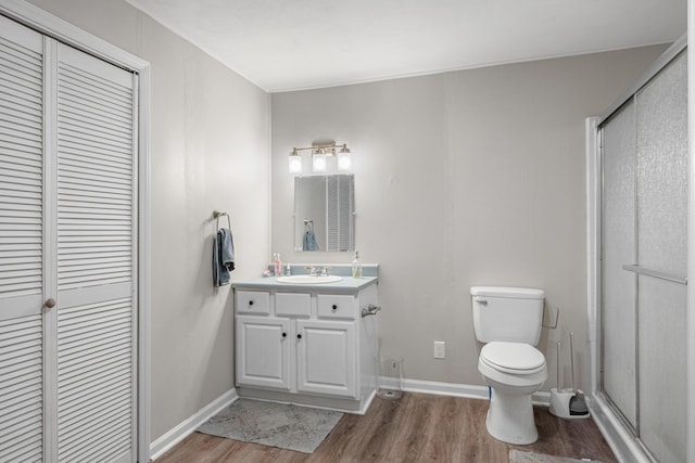 full bath featuring baseboards, toilet, wood finished floors, vanity, and a shower stall