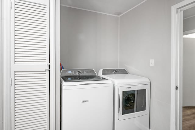 laundry area featuring laundry area, wood finished floors, washing machine and dryer, and crown molding