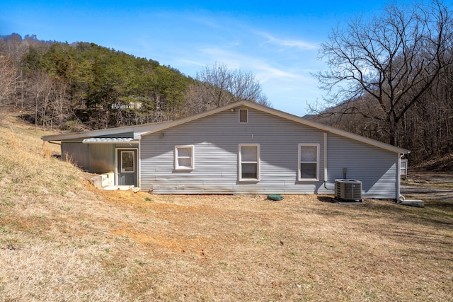 back of property with central AC unit and a lawn