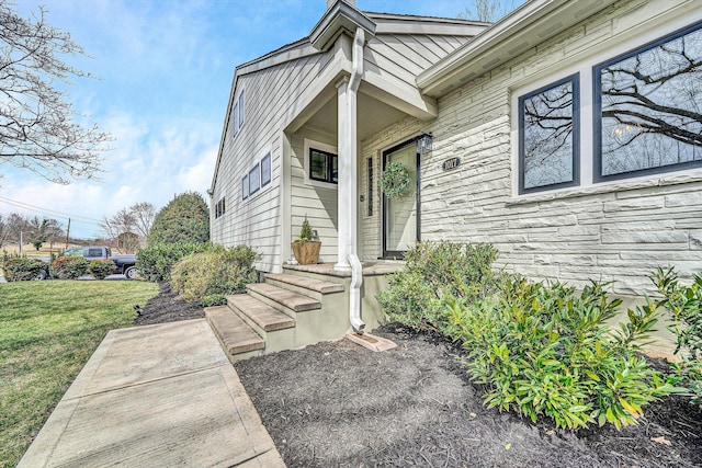 doorway to property with a yard and stone siding