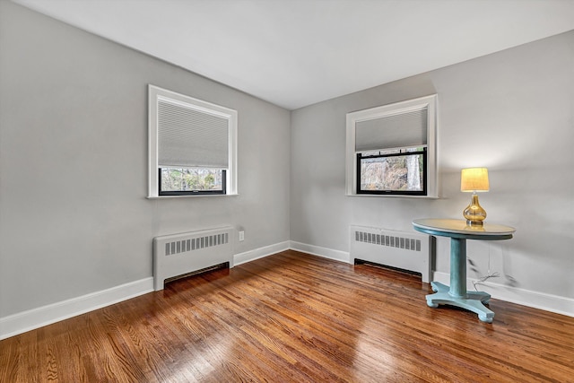 spare room featuring baseboards, wood finished floors, and radiator heating unit