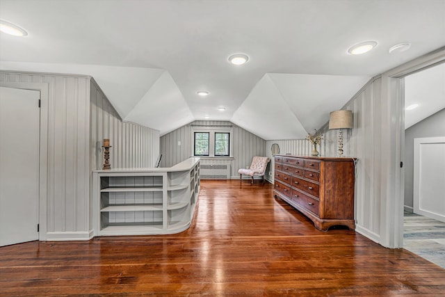 bedroom with vaulted ceiling, radiator heating unit, and wood finished floors