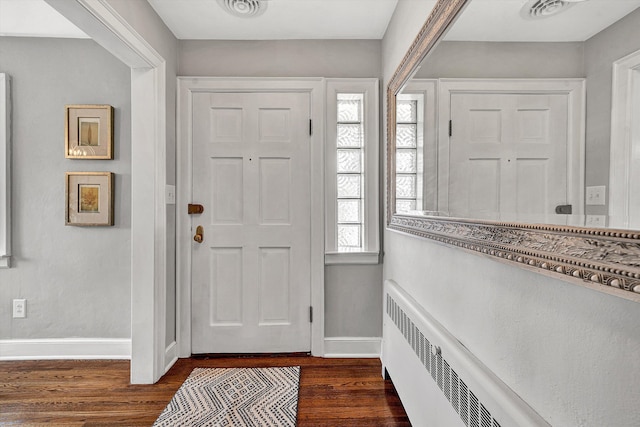 entrance foyer featuring visible vents, radiator, dark wood-type flooring, and baseboards