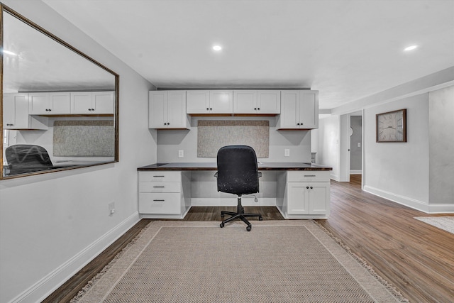 unfurnished office featuring recessed lighting, wood finished floors, baseboards, and built in study area