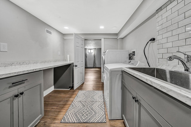 laundry room with visible vents, washer and clothes dryer, dark wood-style flooring, cabinet space, and a sink