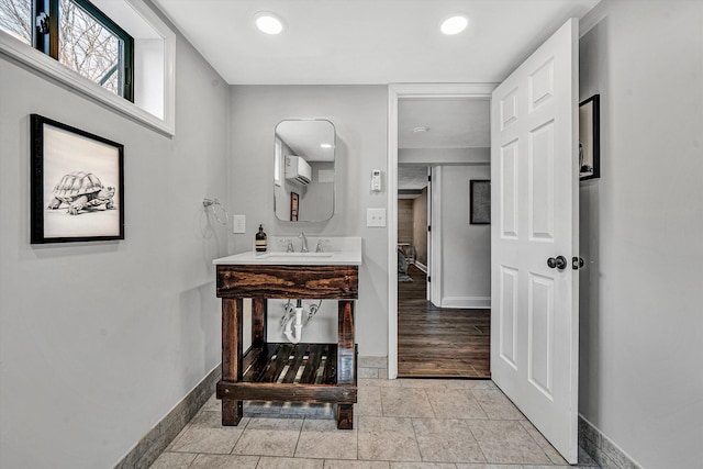 bathroom with vanity, baseboards, a wall mounted AC, recessed lighting, and stone tile flooring