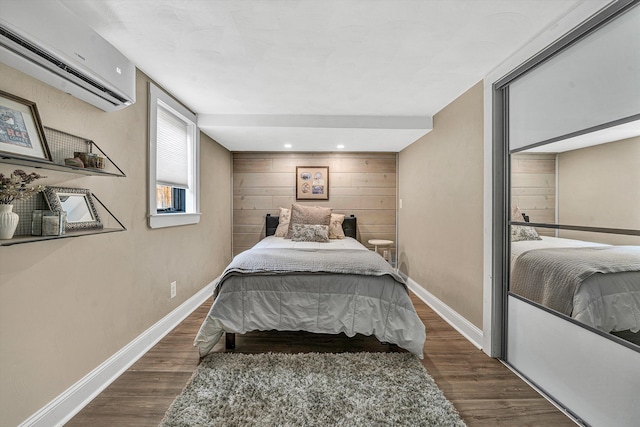 bedroom with wood walls, a wall mounted AC, baseboards, and wood finished floors